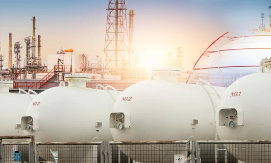 Zbiornik magazynowy, rury i cylindry w fabrycznym otoczeniu przemysłowym. Znaczone pojemniki obejmują zbiorniki paliwa i silosy.